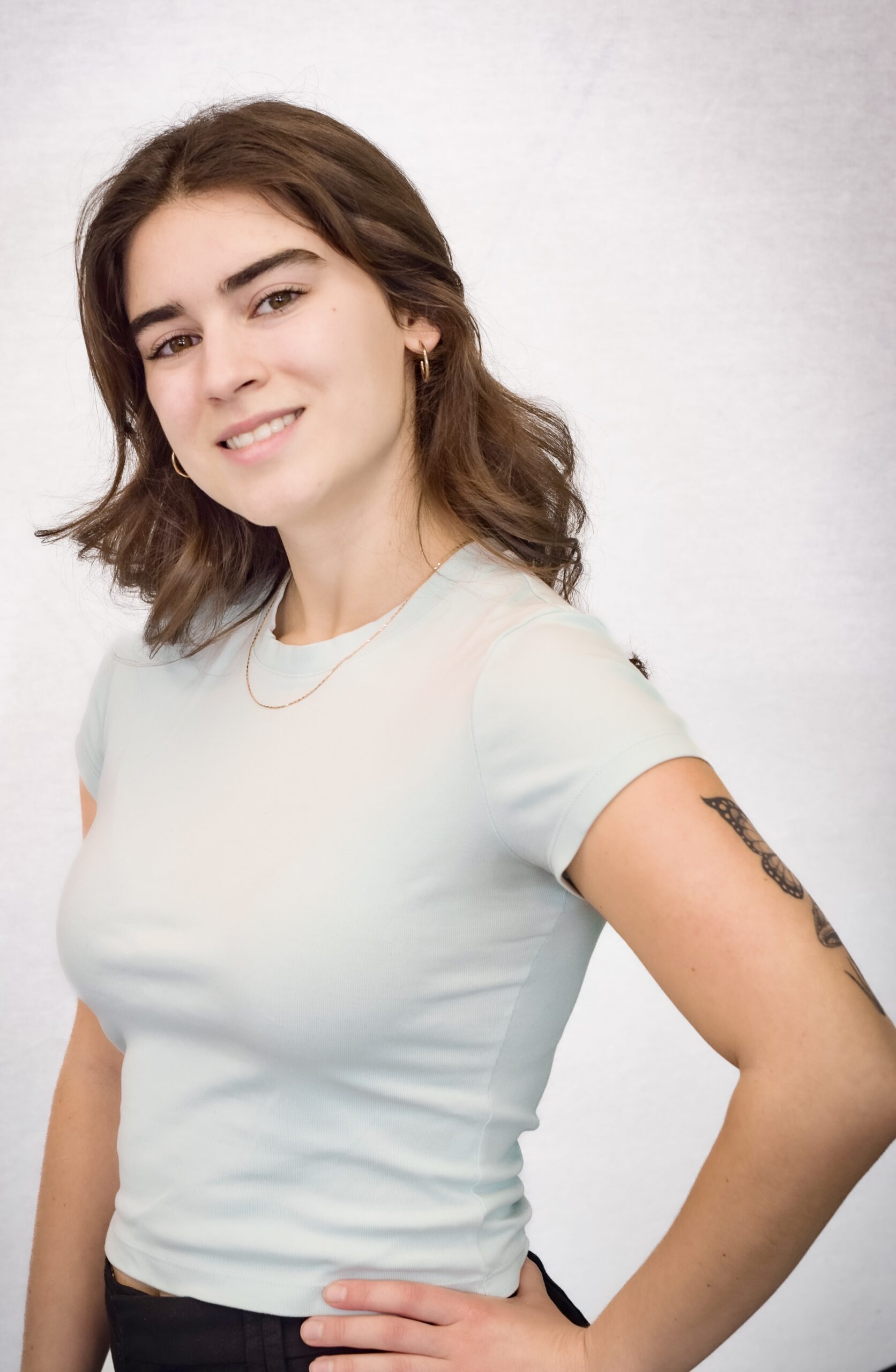 Jeune femme aux cheveux bruns et chandail gris avec tatouage sur le bras