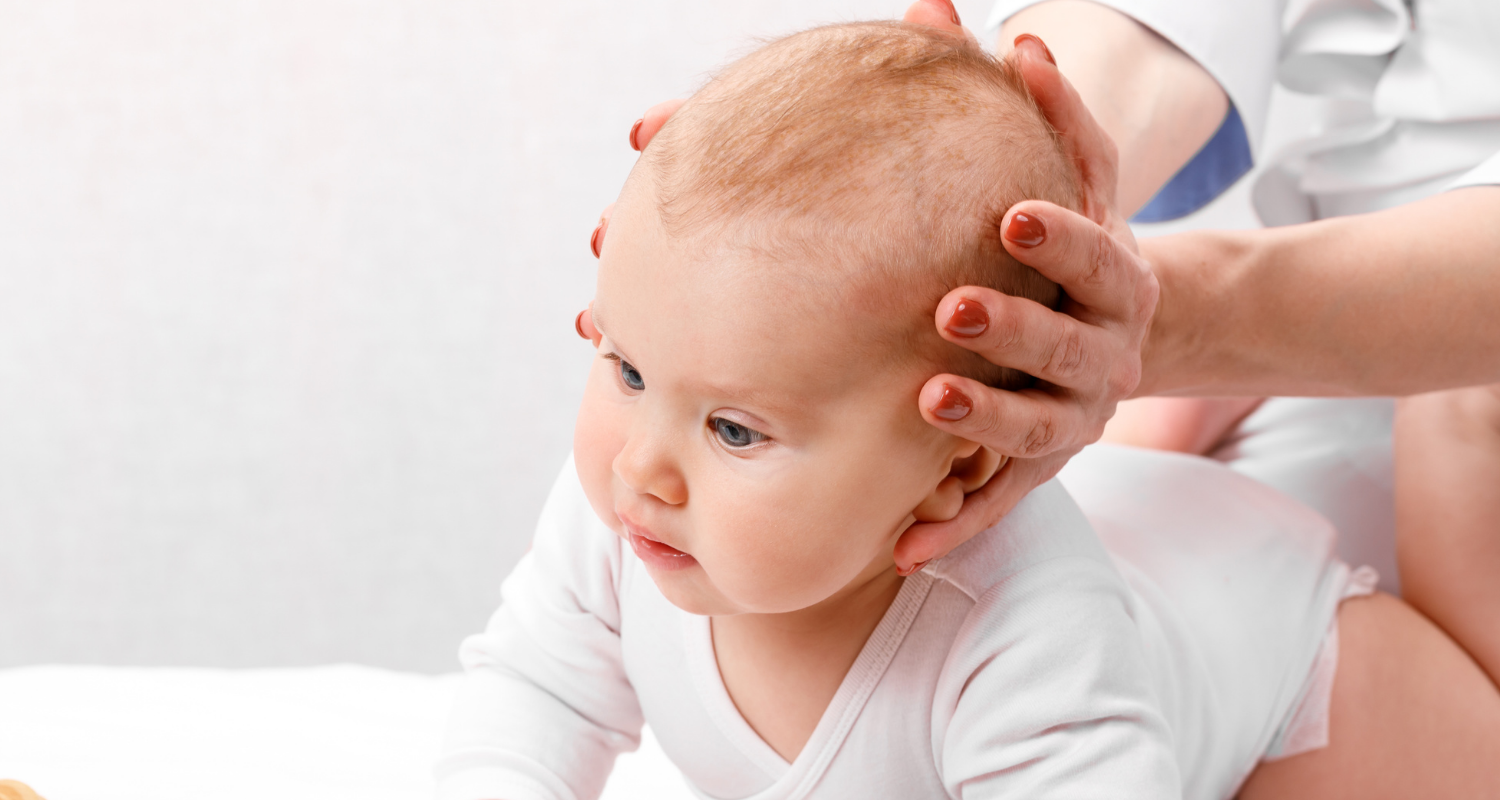 bébé sur une table avec mains de femme sur les côtés de sa tête