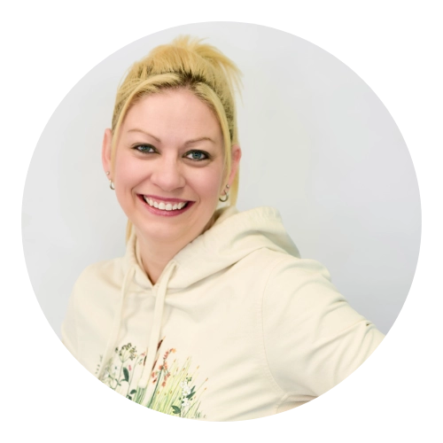 Femme souriante avec chandail à capuchon jaune, cheveux blonds attachés.